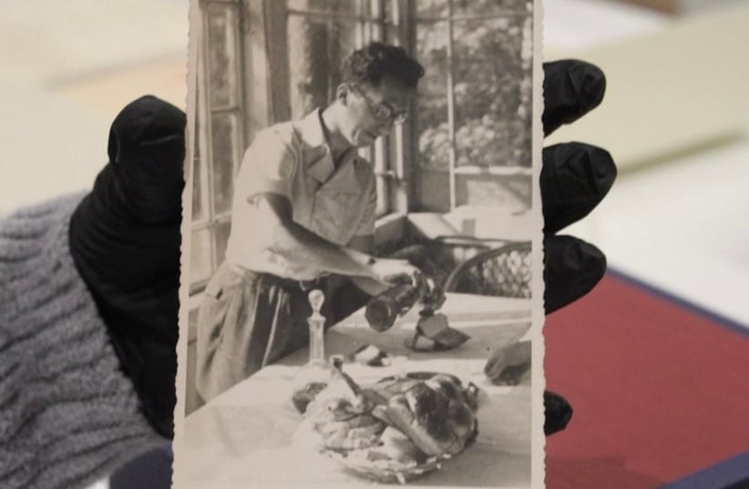 A photograph of Calel Perechodnik pouring wine in a dining room.  (credit: Sophie Berkeley)
