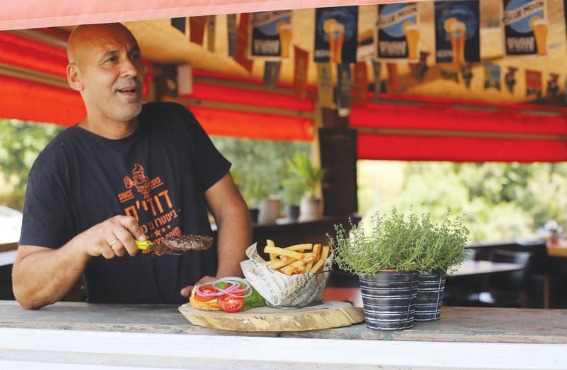 Dudie&rsquo;s Welcome: At the entrance of Givat Yoav, chef Dudie embodies the spirit of local grit by greeting arriving travelers with a glass of pure Golan water as an initial ritual of welcome. (credit: NOAM BEDEIN)