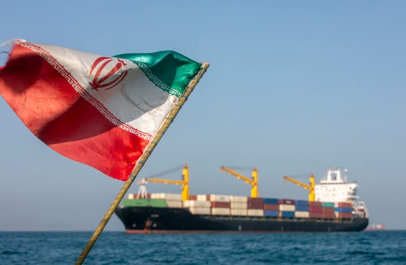 An Iranian flag flutters in the wind as ships remain anchored in the Strait of Hormuz on May 16. Negotiations between the US and Iran over opening this critical waterway have largely stalled.  (credit: Majid Saeedi/Getty Images)