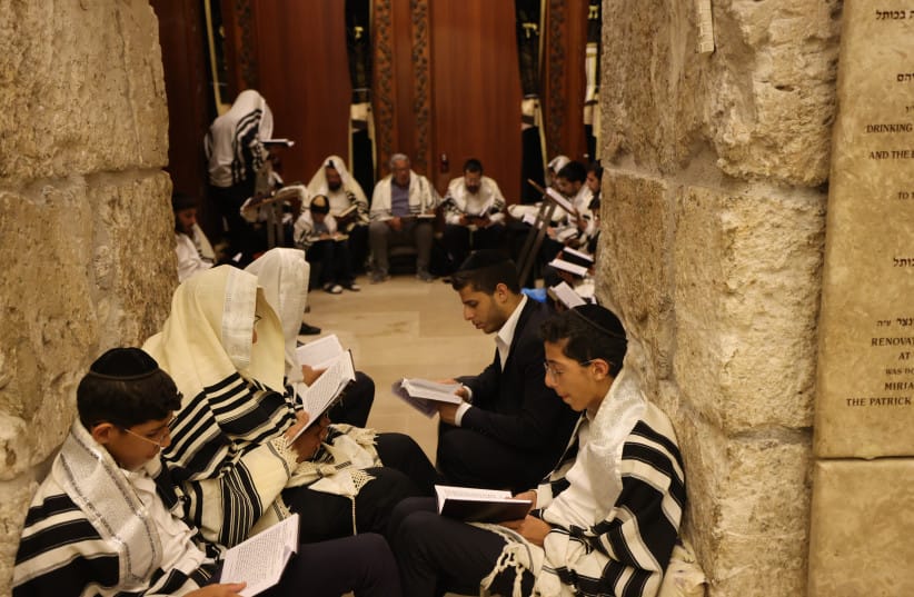Young people in the foreground pray at the Western Wall during Tisha B'Av. (credit: MARC ISRAEL SELLEM/THE JERUSALEM POST)