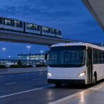 Generic illustration of an airport shuttle bus, elevated train and suitcase at a terminal at night.