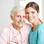 Caregiver embracing a smiling senior woman