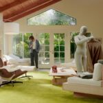 NEO home robot holding a sweater in a living room, in a 1X product photograph.
