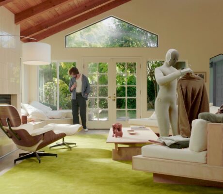 NEO home robot holding a sweater in a living room, in a 1X product photograph.