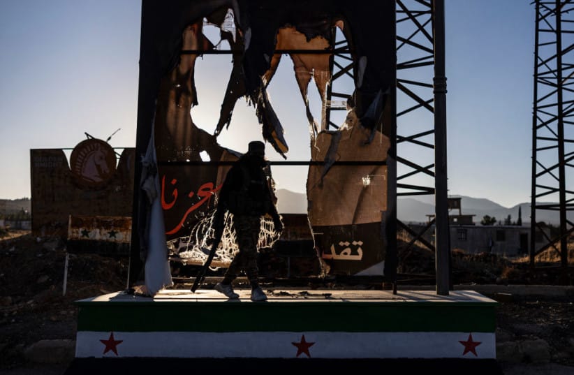 A rebel fighters walks past a defaced portrait of the toppled Syrian president Bashar al-Assad, in the town of Yafour near Damascus, on December 23, 2024. (credit: SAMEER AL-DOUMY/AFP via Getty Images) A rebel fighters walks past a defaced portrait of the toppled Syrian president Bashar al-Assad, in the town of Yafour near Damascus, on December 23, 2024. (credit: SAMEER AL-DOUMY/AFP via Getty Images)