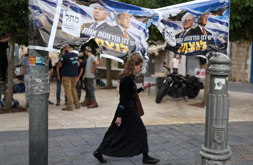 A woman passes by a banner depicting Prime Minister Benjamin Netanyahu and US President Donald Trump day after the country held a national election, in Jerusalem, October 28, 2026 (credit: REUTERS/RONEN ZEVULUN)