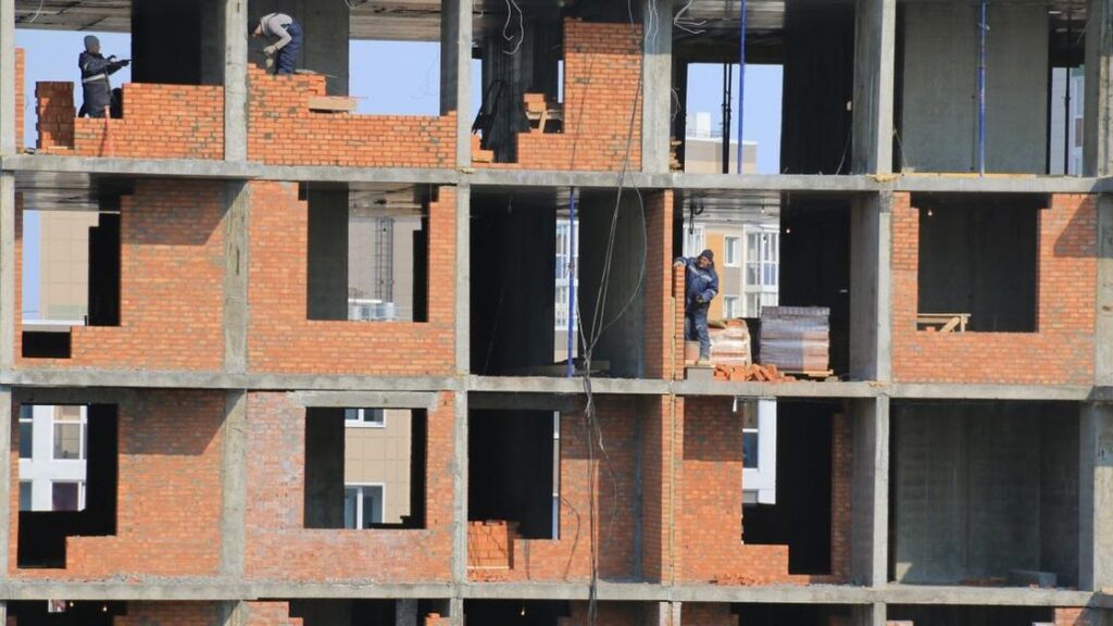 Workers build brick walls at an apartment construction site. Illustrative archive, not identified as Boston or MissionHill.