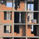 Workers build brick walls at an apartment construction site. Illustrative archive, not identified as Boston or MissionHill.