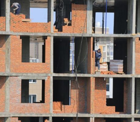 Workers build brick walls at an apartment construction site. Illustrative archive, not identified as Boston or MissionHill.