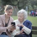 Archive two women using a smartphone together; not identified as caregivers or program participants