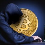 Archive crypto-security concept image of a hooded figure at a laptop beside a Bitcoin medallion. Not a photograph of the Binance incident.