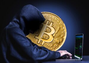 Archive crypto-security concept image of a hooded figure at a laptop beside a Bitcoin medallion. Not a photograph of the Binance incident.