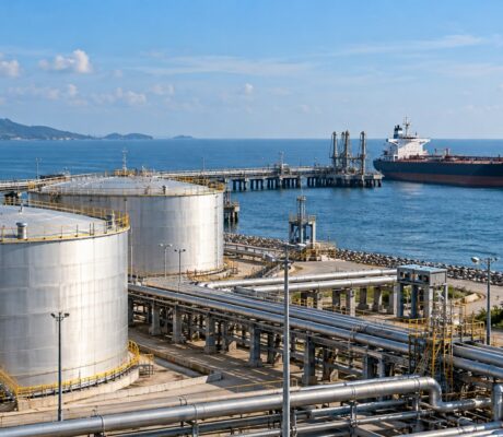 Fuel storage tanks and pipelines beside a tanker and Indian flag.