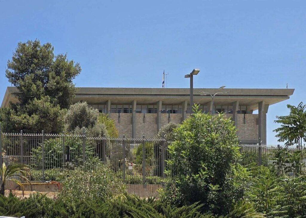Archive photo: the Knesset building behind greenery and a fence in Jerusalem, July 16, 2025. Not the 2026 count.
