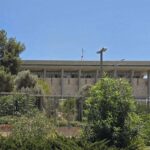 Archive photo: the Knesset building behind greenery and a fence in Jerusalem, July 16, 2025. Not the 2026 count.