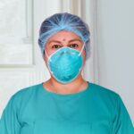 A masked healthcare professional in an illustrative clinical-setting archive photo. Not an individual return-to-work decision.