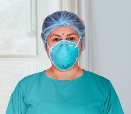 A masked healthcare professional in an illustrative clinical-setting archive photo. Not an individual return-to-work decision.