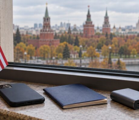 U.S. desk flag, phone, notebook and power bank beside a window.