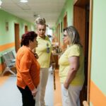 Two nurses speaking with an older resident. Illustrative archive, not CMS program participants.