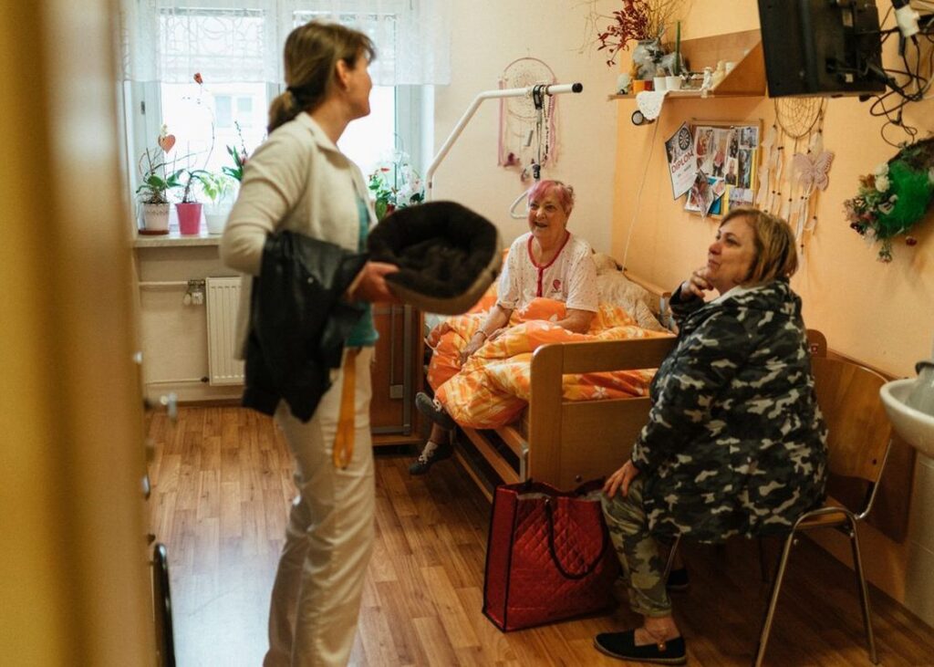 A caregiver and older adults in a residential care setting. Illustrative archive, not a U.S. facility assessed by CMS.