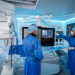Philips coronary-imaging equipment in an interventional suite with two masked clinicians.