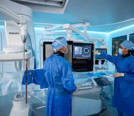 Philips coronary-imaging equipment in an interventional suite with two masked clinicians.