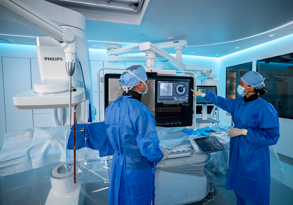 Philips coronary-imaging equipment in an interventional suite with two masked clinicians.
