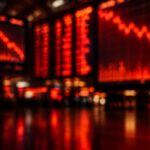 Blurred red stock market screens showing falling charts glowing in a dark trading hall.
