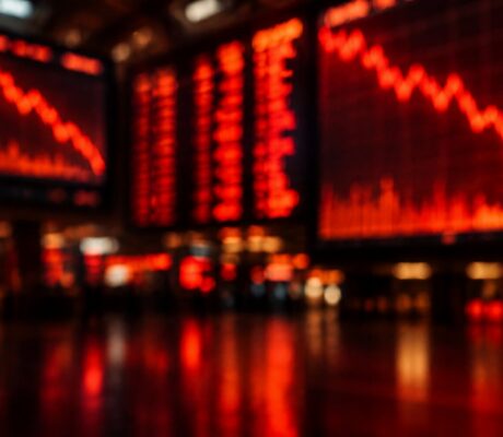 Blurred red stock market screens showing falling charts glowing in a dark trading hall.