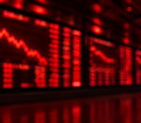 Blurred red stock market trading screens showing falling charts on a dark exchange wall