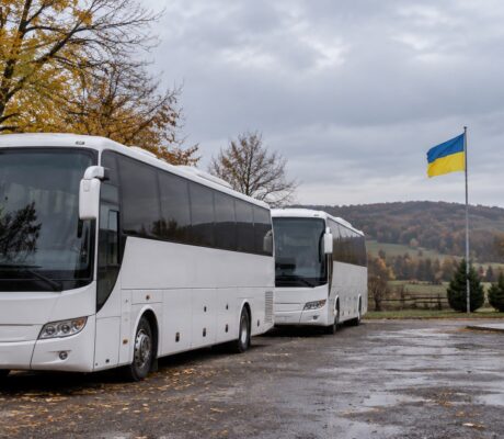 Two coaches parked beside a Ukrainian flag.